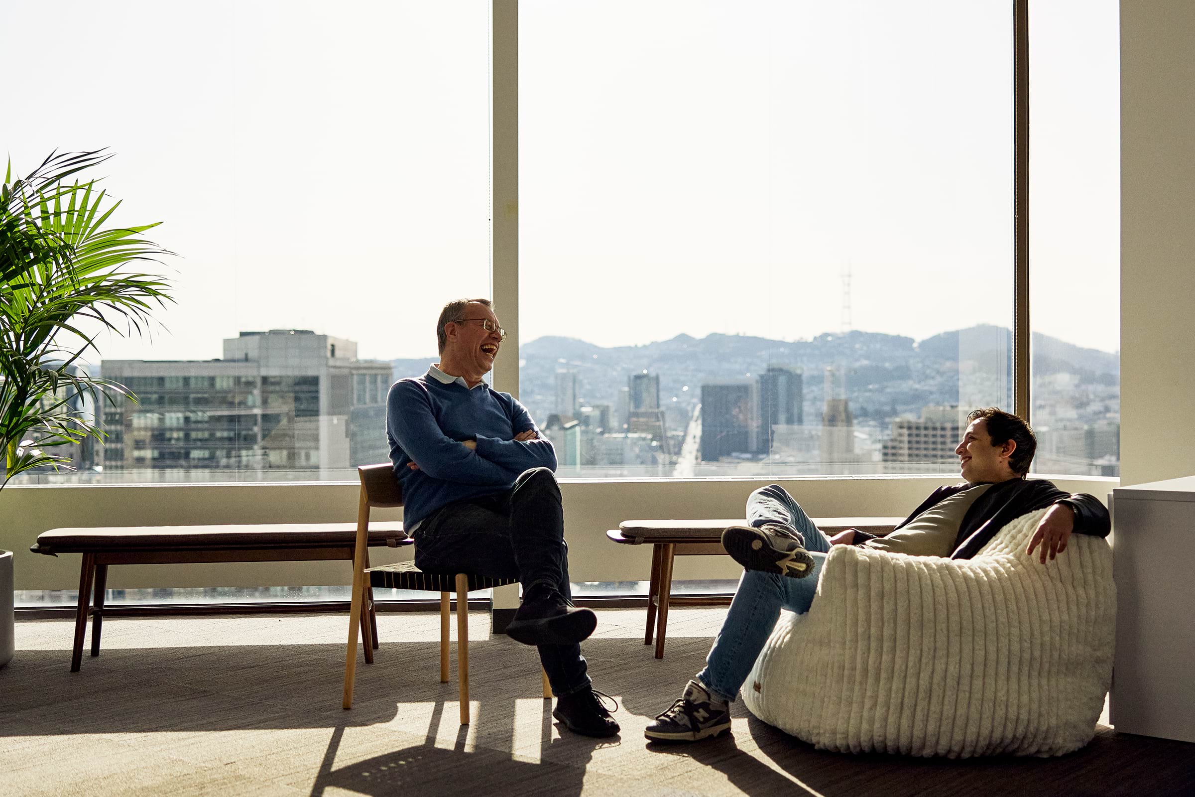 Two team members sharing a laugh in a lounge overlooking the San Francisco skyline