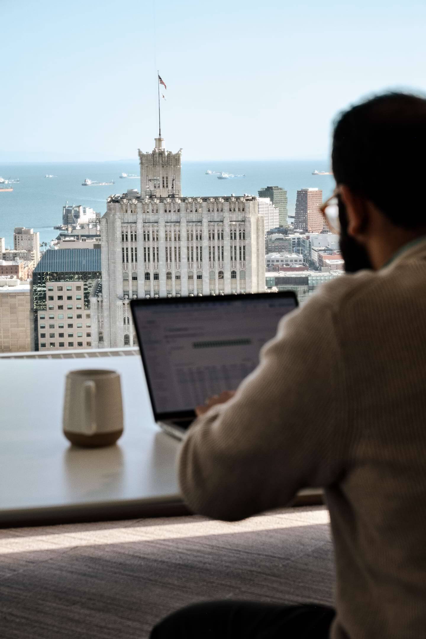 An engineer working on a laptop overlooking the San Francisco Bay