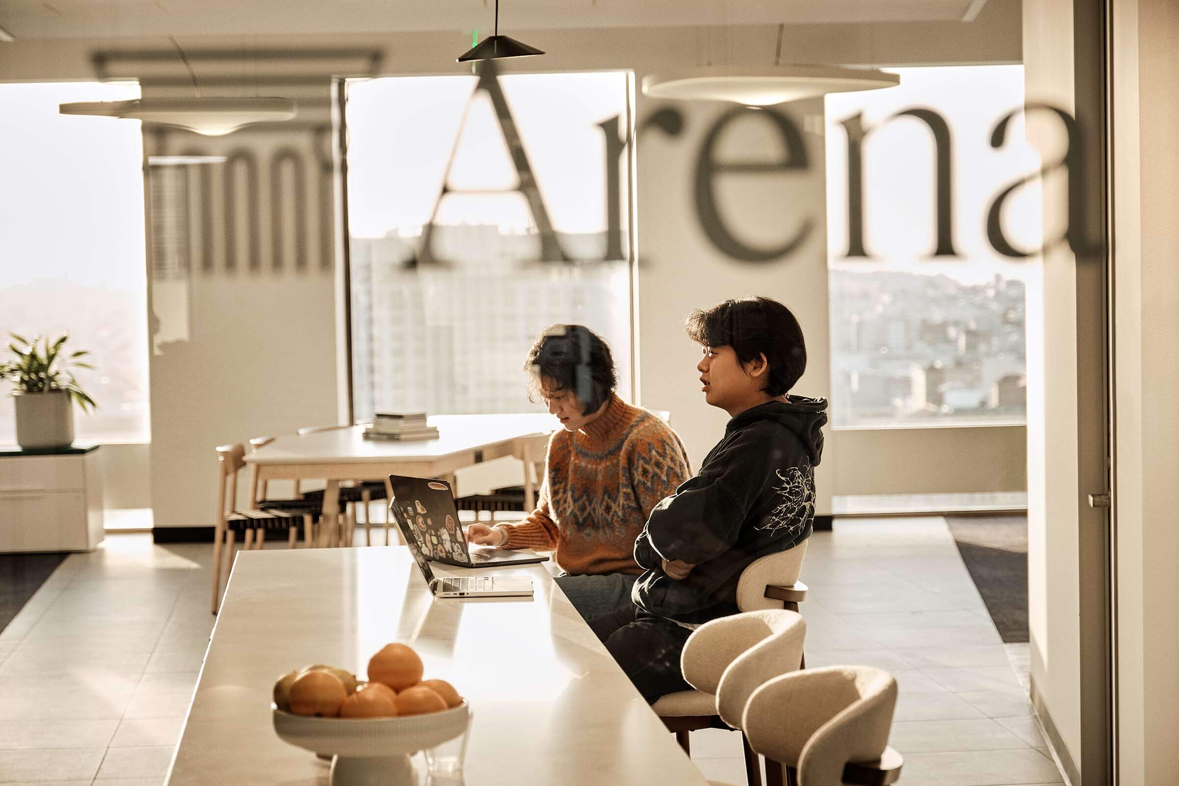 Two team members working at a counter behind the Arena sign